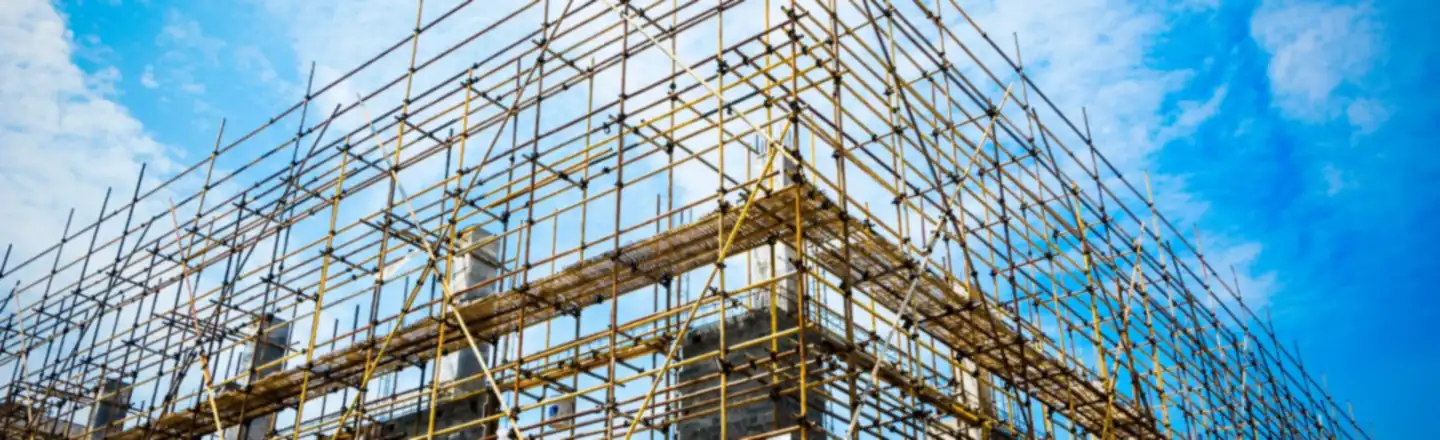 Steel scaffolding around a building under construction against a blue sky