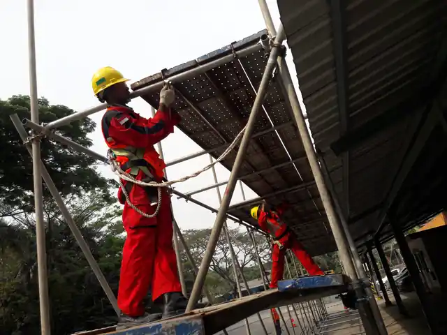 Worker in a red safety harness fitting a scaffolding platform