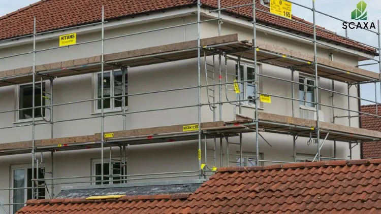 Scaffolding system around a building under construction, featuring wooden planks and safety signage, highlighting SCAXA's durable formwork solutions for efficient construction projects.