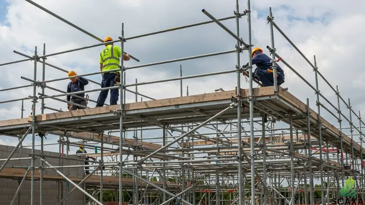 Construction workers assembling prop system scaffolding with tripods and head plates for stability and safety.